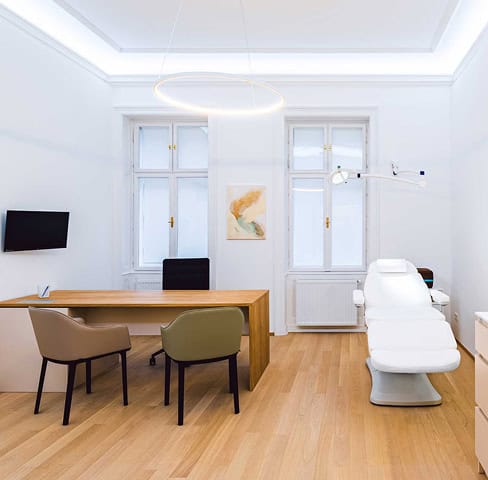 Modernes Behandlungszimmer im Zentrum Aestheticum mit Behandlungsliege und Beratungstisch.