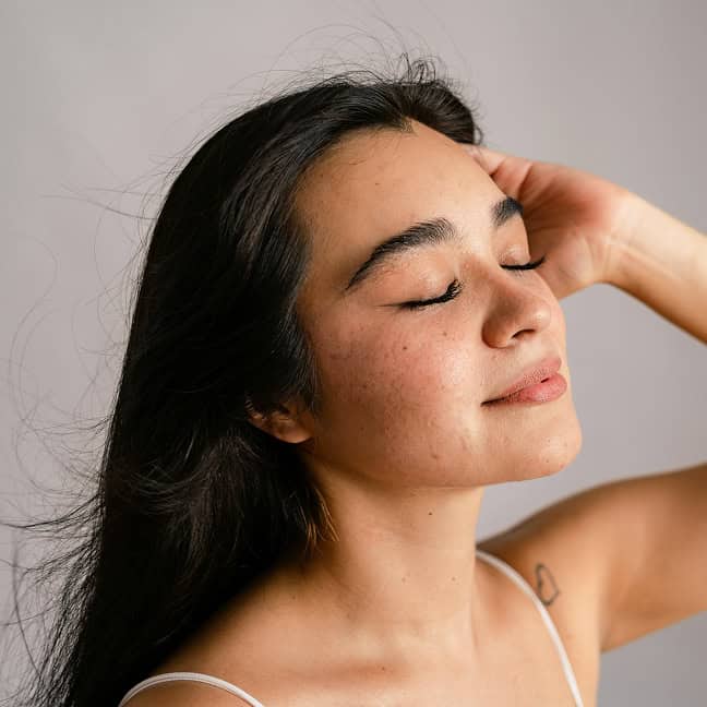 Frau mit reiner Haut, entspannt und zufrieden, bei Hautpflegebehandlung.