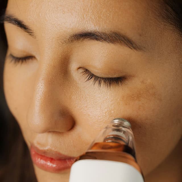 Frau erhält Hautbehandlung mit Serum für jugendliche Haut.