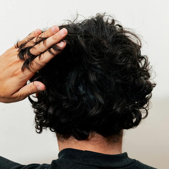 Mann mit lockigem Kurzhaarschnitt von hinten