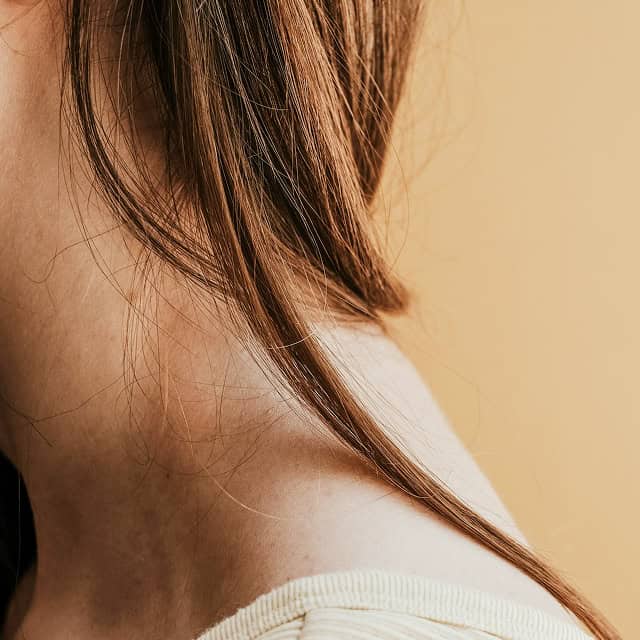 Nahaufnahme von Hals und Schulter einer Frau, Fokus auf Haut und Haar.